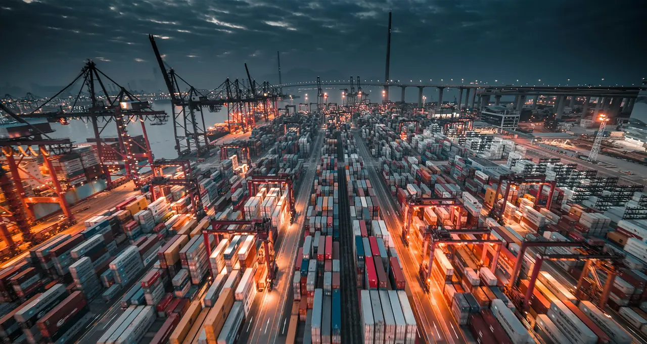 Container terminal with cranes and stacked shipping containers at dusk